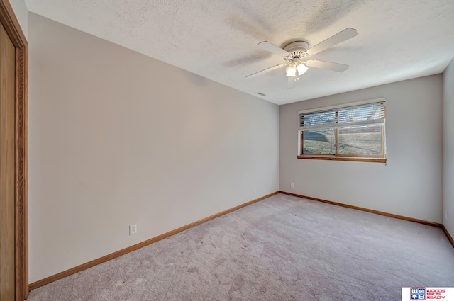 carpeted empty room with ceiling fan and a textured ceiling