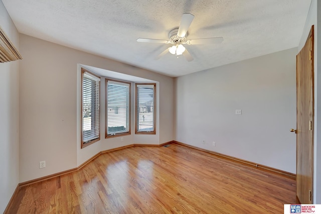 spare room featuring light wood-type flooring, a textured ceiling, and ceiling fan