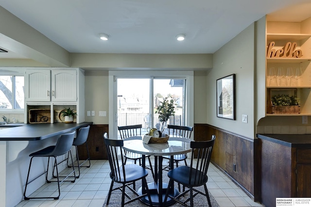 dining area with wooden walls and light tile patterned floors