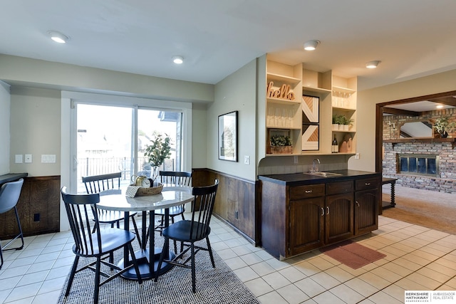 kitchen featuring a brick fireplace, built in shelves, light tile patterned floors, and dark brown cabinets