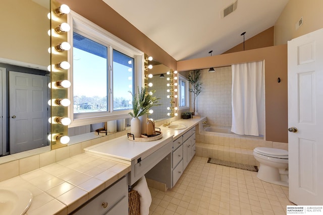 bathroom featuring lofted ceiling, tile patterned floors, vanity, toilet, and a relaxing tiled tub