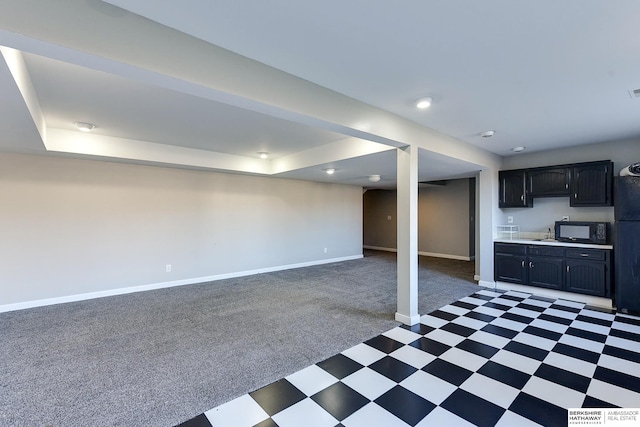 basement with sink, black refrigerator, and light colored carpet