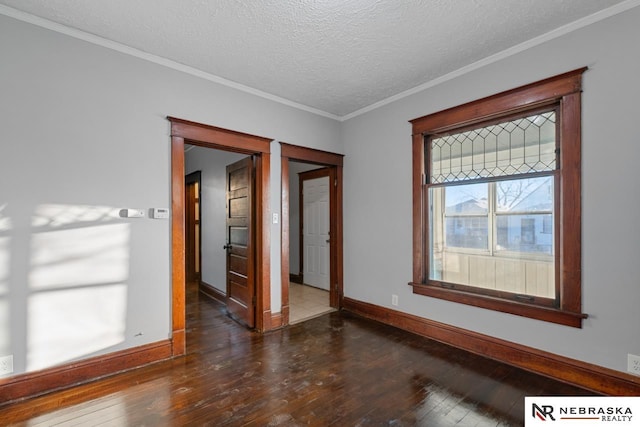 spare room featuring crown molding, dark wood-type flooring, and a textured ceiling