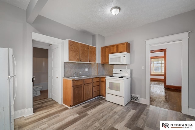 kitchen with white appliances, a textured ceiling, light hardwood / wood-style floors, sink, and decorative backsplash