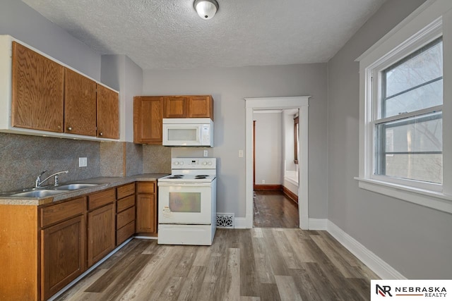 kitchen featuring sink, backsplash, white appliances, and a textured ceiling