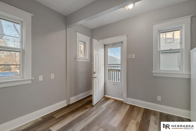 doorway to outside with a textured ceiling, plenty of natural light, and hardwood / wood-style flooring