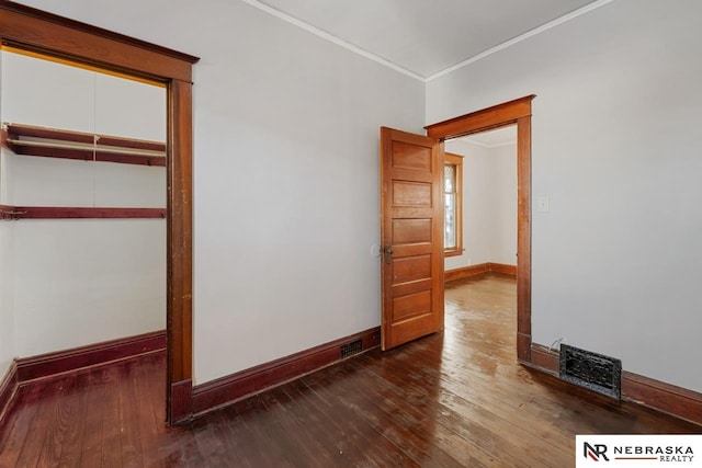 unfurnished bedroom with a closet, dark hardwood / wood-style floors, and ornamental molding