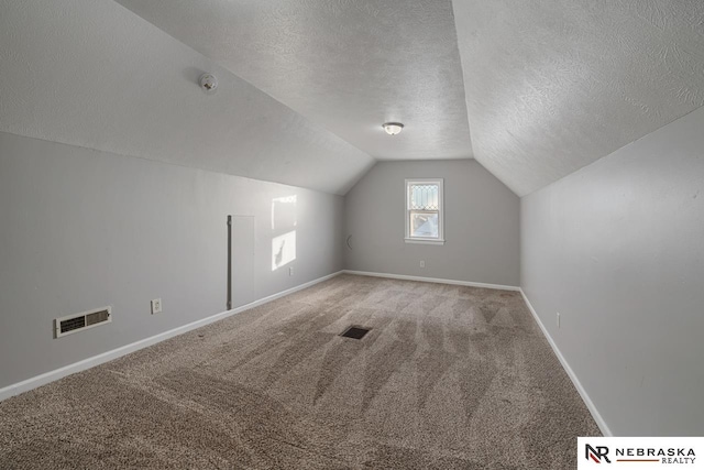 bonus room with a textured ceiling, carpet floors, and vaulted ceiling