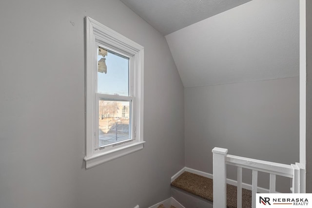 staircase with a textured ceiling and vaulted ceiling