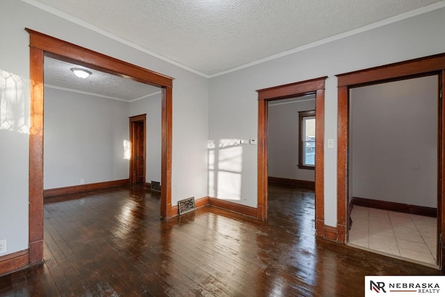 spare room with a textured ceiling, dark hardwood / wood-style flooring, and crown molding