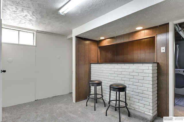 bar featuring a textured ceiling, light colored carpet, and wooden walls