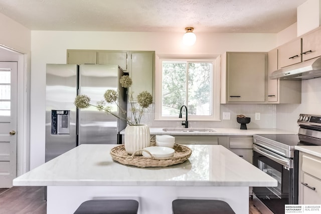 kitchen with sink, appliances with stainless steel finishes, a breakfast bar area, and a kitchen island