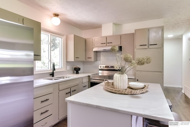 kitchen featuring sink, a kitchen island, appliances with stainless steel finishes, and a textured ceiling