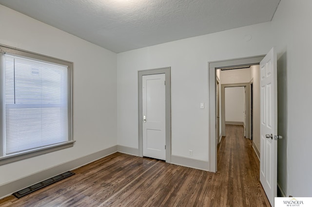 unfurnished bedroom with a textured ceiling and dark hardwood / wood-style floors