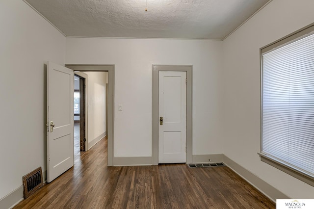 unfurnished room with a textured ceiling and dark hardwood / wood-style flooring