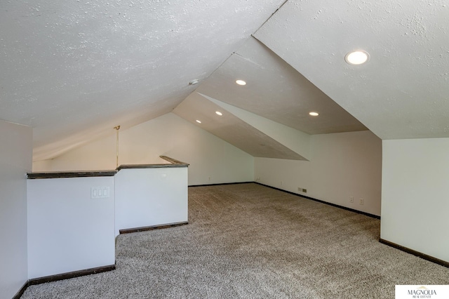 additional living space with light carpet, a textured ceiling, and lofted ceiling