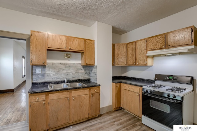 kitchen featuring a textured ceiling, sink, backsplash, light wood-type flooring, and gas range