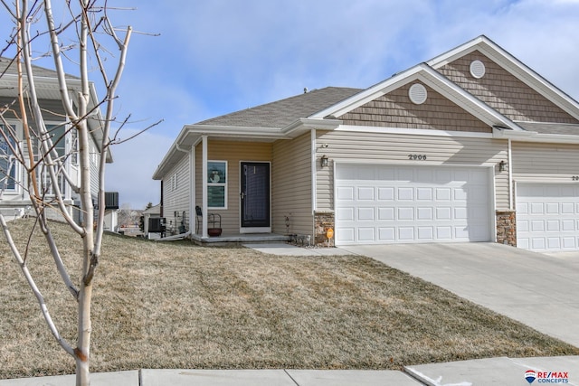 view of front of home with a garage, a front yard, and central air condition unit