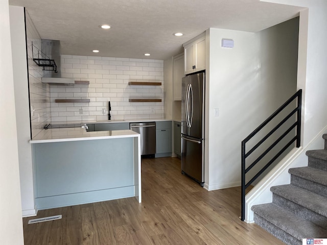 kitchen with appliances with stainless steel finishes, decorative backsplash, light hardwood / wood-style floors, sink, and gray cabinetry