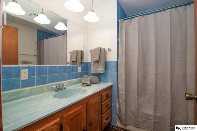 bathroom with tasteful backsplash, walk in shower, tile walls, tile patterned floors, and vanity