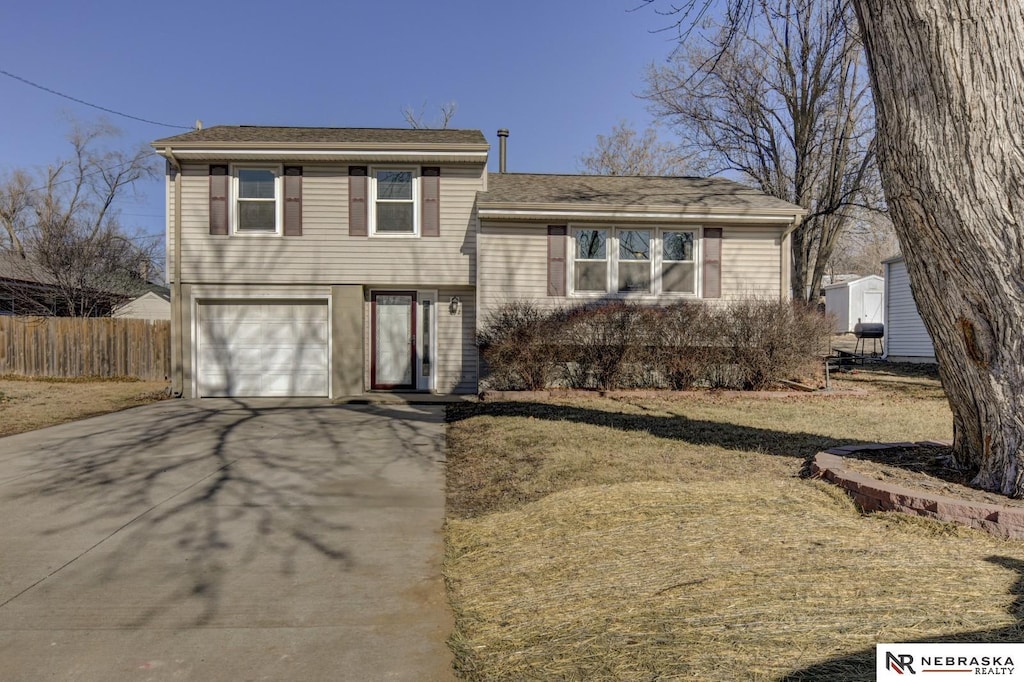 tri-level home featuring a garage and a front lawn