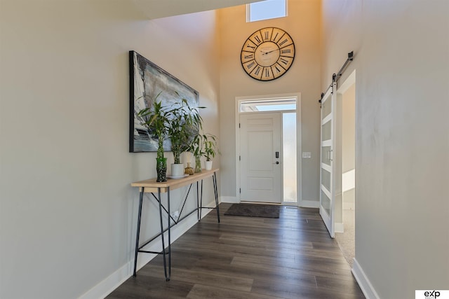 entryway featuring dark wood-type flooring, a barn door, and a high ceiling