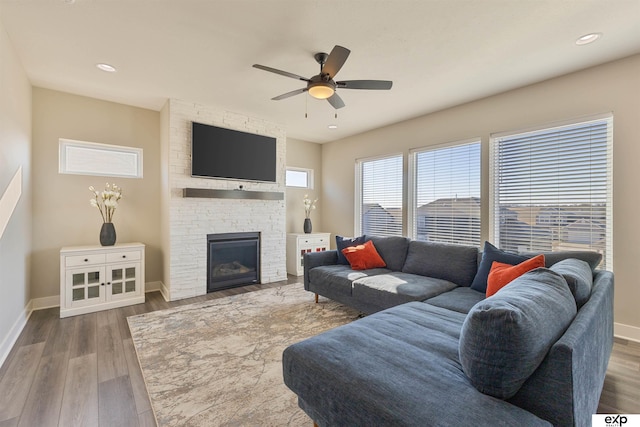 living room featuring hardwood / wood-style flooring, ceiling fan, and a fireplace