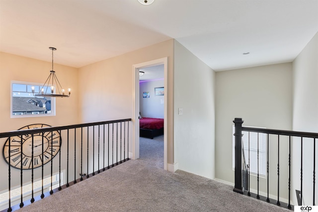 hallway with carpet flooring, a wealth of natural light, and an inviting chandelier