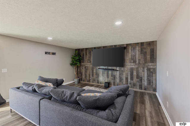 living room featuring wood-type flooring, a textured ceiling, and wood walls