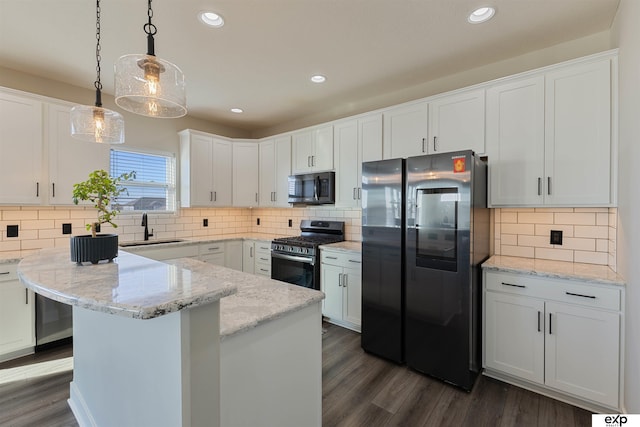 kitchen featuring sink, light stone counters, pendant lighting, stainless steel appliances, and white cabinets