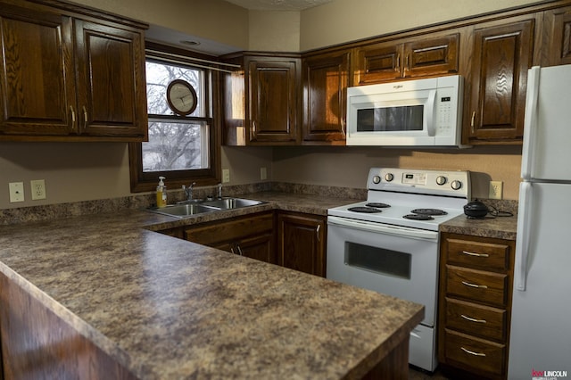 kitchen with white appliances, dark brown cabinetry, and sink