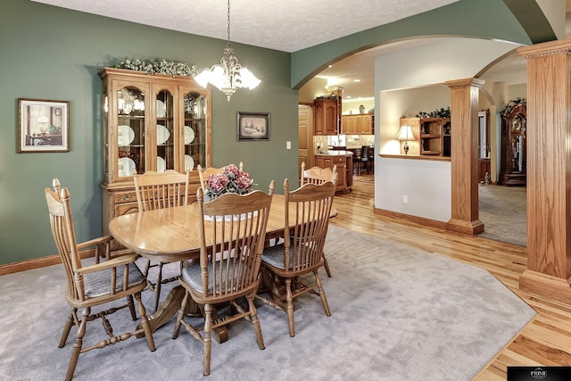 dining room with an inviting chandelier, a textured ceiling, and light wood-type flooring