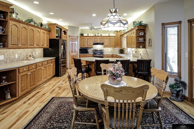 dining area with sink, light wood-type flooring, and ceiling fan