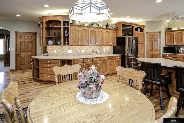 kitchen with stainless steel refrigerator with ice dispenser, ceiling fan, sink, backsplash, and light hardwood / wood-style floors