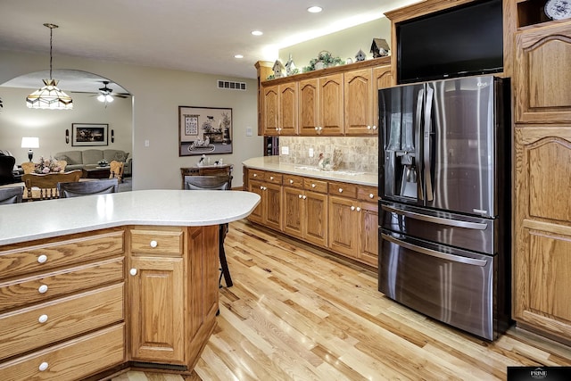 kitchen featuring tasteful backsplash, a kitchen breakfast bar, hanging light fixtures, stainless steel fridge with ice dispenser, and light wood-type flooring