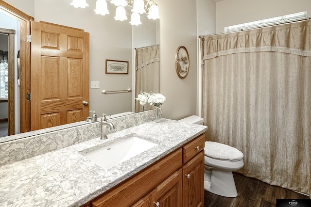 bathroom featuring hardwood / wood-style flooring, toilet, vanity, and a notable chandelier