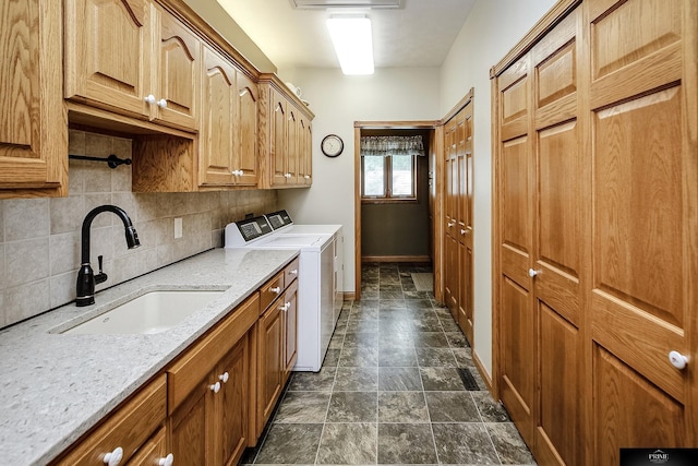 kitchen with sink, backsplash, washer and dryer, and light stone counters