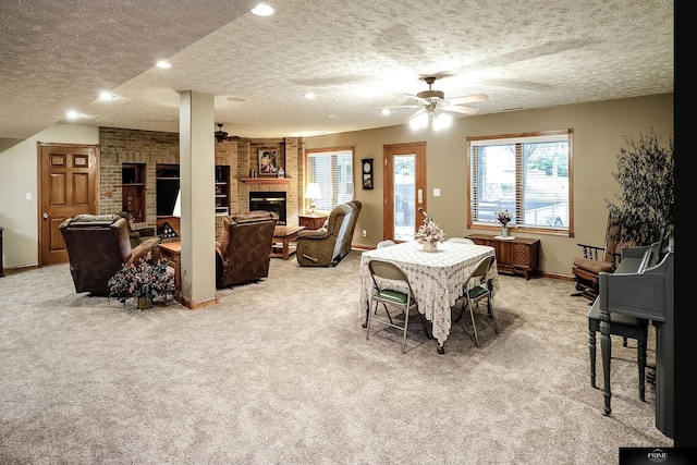 dining room featuring ceiling fan, a textured ceiling, light carpet, and a fireplace