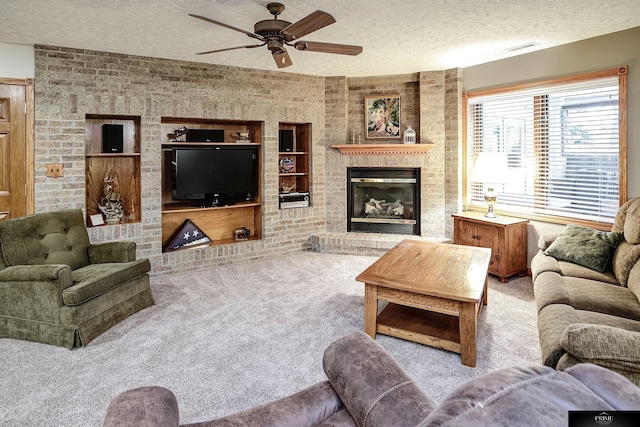 carpeted living room featuring built in features, ceiling fan, a brick fireplace, and a textured ceiling