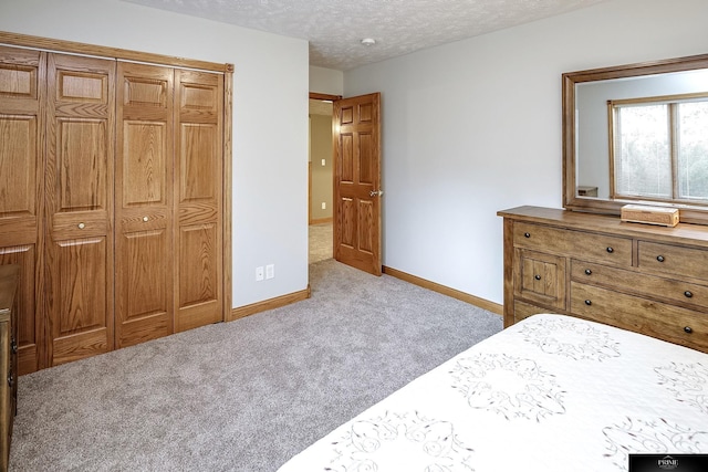 bedroom with a textured ceiling, light colored carpet, and a closet