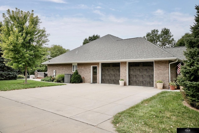 view of side of property with a garage, a yard, and cooling unit