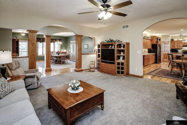 carpeted living room with decorative columns and ceiling fan