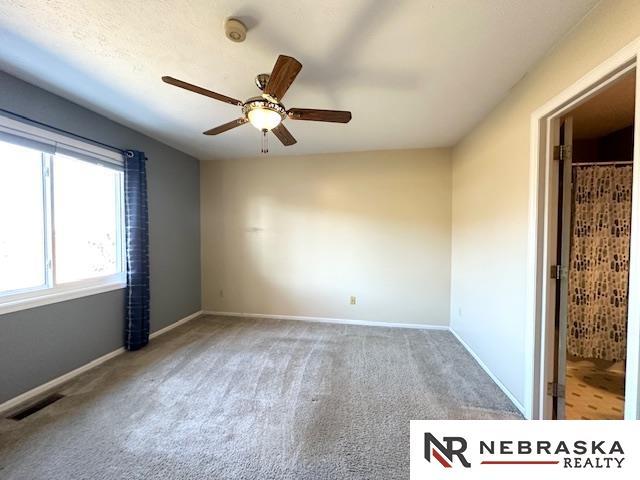 carpeted empty room featuring ceiling fan