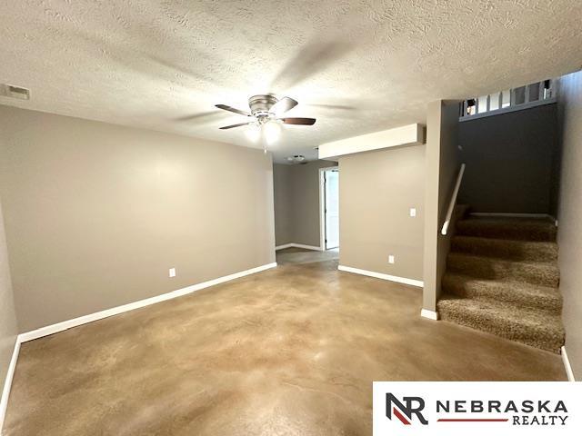 basement featuring ceiling fan and a textured ceiling