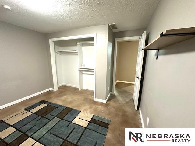 unfurnished bedroom featuring a textured ceiling, a closet, and dark colored carpet