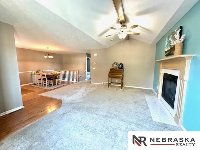 interior space featuring ceiling fan with notable chandelier, carpet flooring, and vaulted ceiling