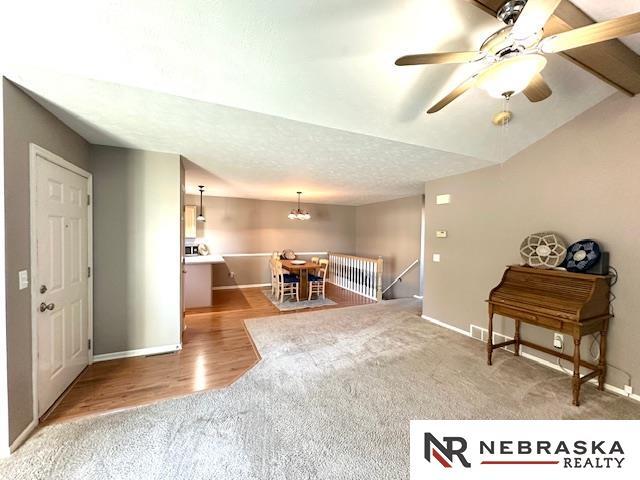 interior space featuring ceiling fan with notable chandelier, a textured ceiling, light carpet, and lofted ceiling with beams