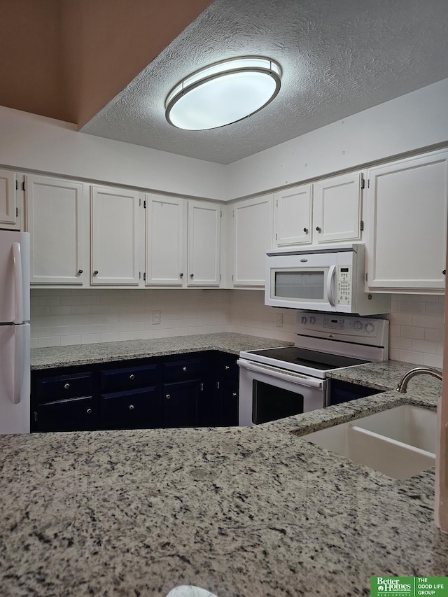 kitchen with white cabinetry, sink, backsplash, white appliances, and a textured ceiling