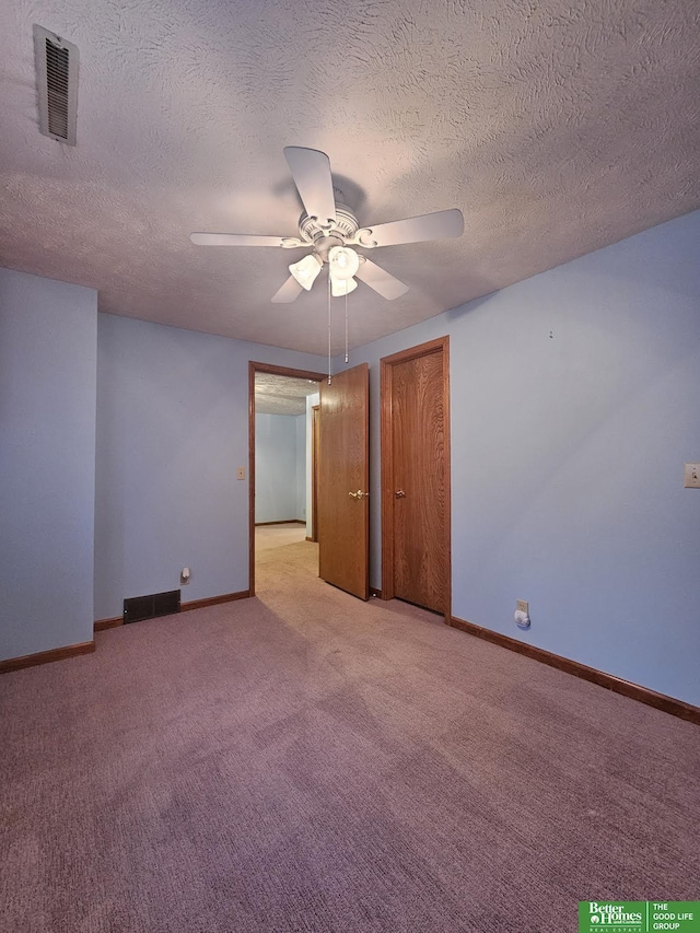 spare room featuring ceiling fan, light colored carpet, and a textured ceiling