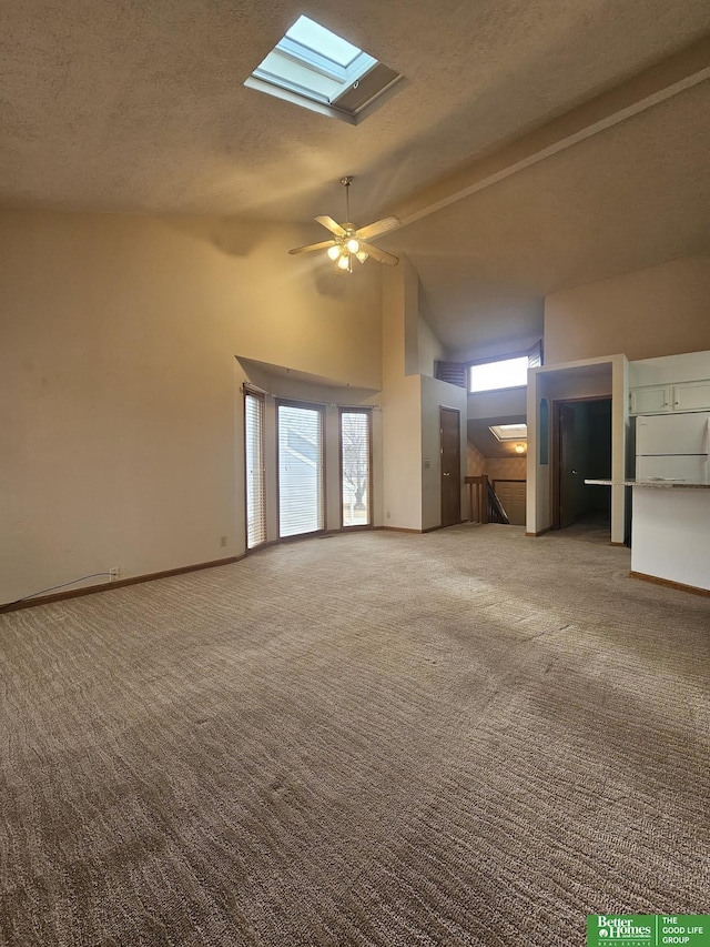 unfurnished living room featuring high vaulted ceiling, carpet floors, a textured ceiling, and a skylight